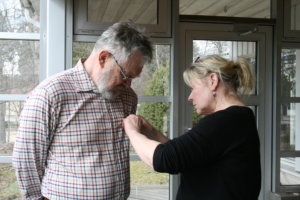 Suomen Luonnonsuojeluliiton Pälkäneen seutu ry:n hallituksen jäsen ja sihteeri Marjaana Laaksonen kiinnitti kultaisen ansiomerkin Martti Sivosen paitaan.   